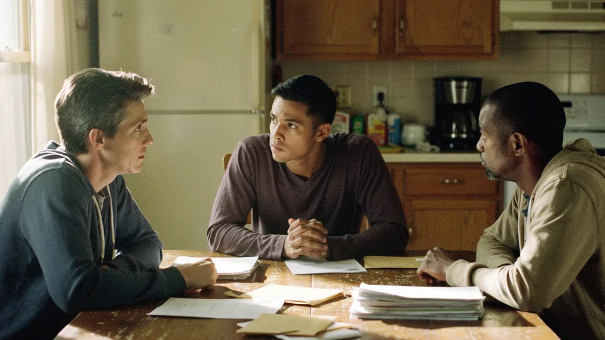 Three adult siblings sitting around a kitchen table having a serious family discussion with papers in front of them